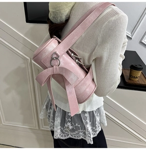 Detail of a pink Boston bag featuring a large decorative bow and shiny faux leather texture