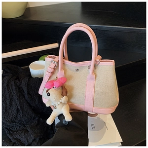 Detail of beige canvas and pink leather bucket bag with cute plush puppy charm