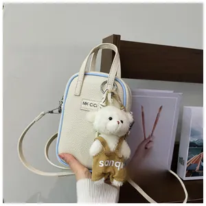 Detail of white lychee pattern mini bag with blue edges and cute bear charm accessory