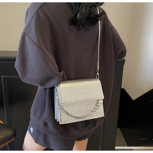Detail of silver crocodile pattern bag with chain strap and pearl charms on model