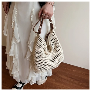 Detail of hand-woven beige straw tote bag with premium brown leather handles and metal rings