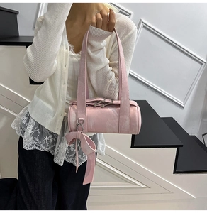Detailed view of pink Boston bag with bow charm worn by model in street style setting