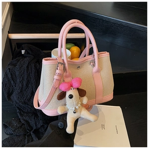 Detail of cream canvas bucket bag with pink leather trim and cute plush puppy charm