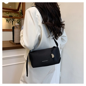 Détail du sac bandoulière noir avec texte mode et breloque en forme de cœur doré