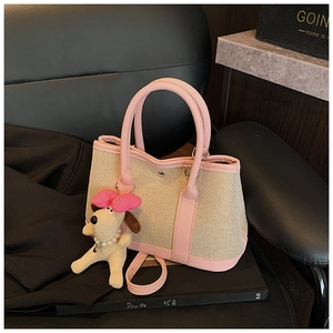 Detail of pink leather and canvas tote with a cute puppy plush charm on a luxury seat