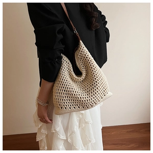 Detail of beige crochet hobo bag with hollow knit pattern and brown leather strap