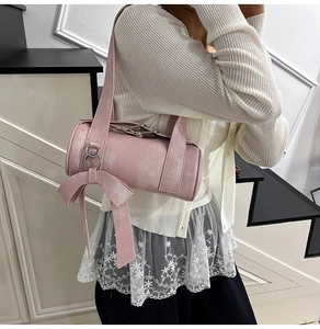 Détail d'un sac tonneau rose clair en cuir souple orné d'un grand nœud décoratif