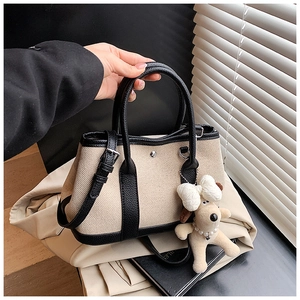 Detail of contrast stitching canvas bucket bag with plush charm and leather trim