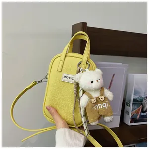 Detail of yellow lychee texture mini handbag with cute white bear charm and shoulder strap