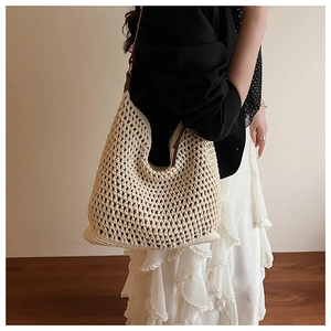 Macro detail of creamy beige hollow crochet woven tote bag with brown leather strap