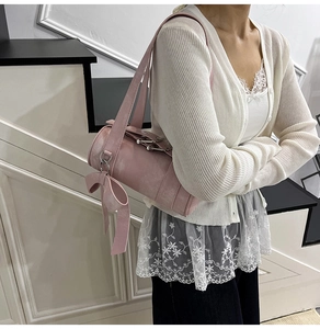 Vue détaillée d'un sac à bandoulière rose cylindrique avec grand nœud et anneaux argentés