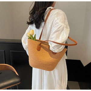 Detail of woven rope tote bag with dark brown leather straps and visible white stitching