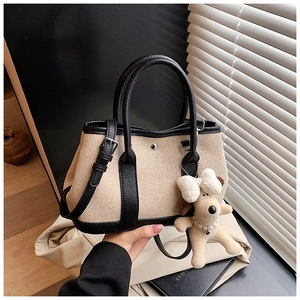 Detail of canvas bucket bag with black leather trim, metal studs and cute dog charm