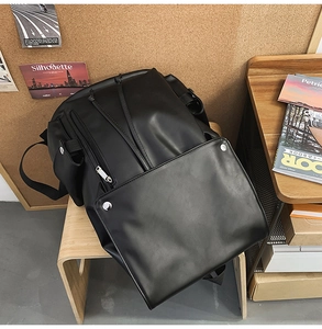 Close-up of a vintage black faux leather backpack with side pockets on a wooden stool
