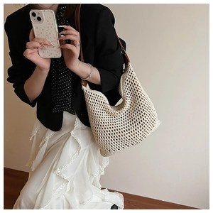 Detail of hollow woven straw tote bag with brown leather strap in an elegant style