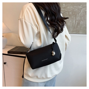 Détail d'un sac bandoulière noir avec texte blanc et pendentif en forme de cœur argenté