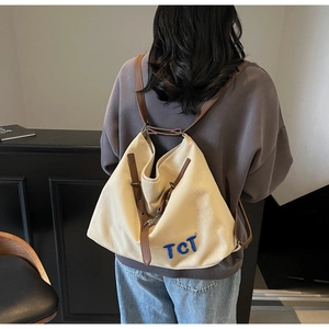 Close-up of durable cream canvas tote bag with brown faux leather straps and TCT embroidery