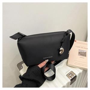 Détail d'un sac à bandoulière noir avec pendentif cœur argenté et logo mode blanc