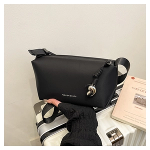 Détail d'un sac bandoulière noir avec texte tendance et pendentif en métal argenté