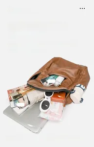Flat lay of brown leather backpack interior showing space for laptop and daily essentials