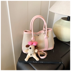 Detail of beige canvas and pink leather bucket bag with cute dog plush charm pendant