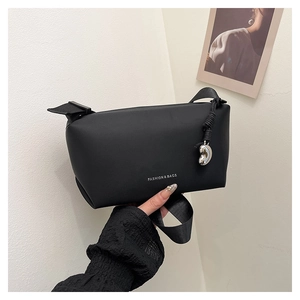 Détail du sac bandoulière noir minimaliste avec logo fashion et pendentif argenté