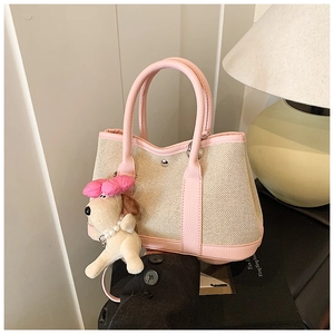 Detail of canvas tote bag with pink leather trim and a cute plush dog charm accessory