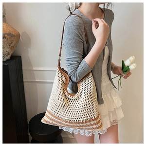 Side view of model wearing a woven straw shoulder bag with brown leather strap