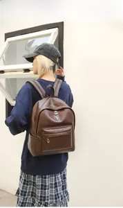 Detailed view of deep brown leather backpack with retro texture and metal logo plaque