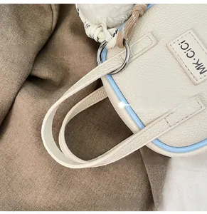 Close-up of beige lychee leather handbag handle with blue piping and brand tag
