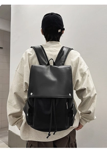 Detailed back view of a black matte leather backpack with flap and drawstring closure