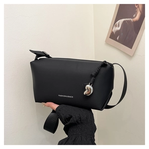 Détail du sac à bandoulière noir avec impression texte blanc et breloque coeur argentée