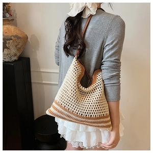Detail of hand-woven hobo bag with brown leather strap and contrast bottom stripes