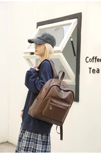Detail of vintage brown PU leather backpack with silver animal plate and front zipper