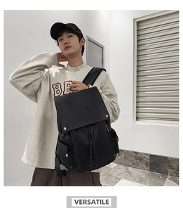 Detail of black leather backpack with flap buckle closure on male model in minimal interior
