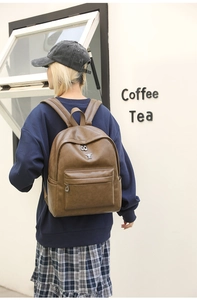 Close-up of vintage dark brown leather backpack with spacious front zipper pocket and logo