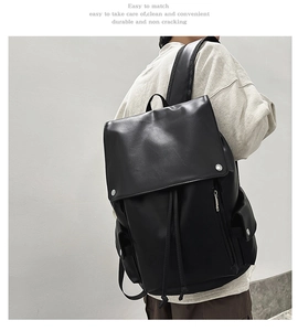 Rear view of a black leather minimalist backpack showing padded straps and a secure flap