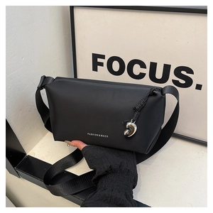 Détail du sac bandoulière noir mat avec lettrage FASHION et breloque en argent