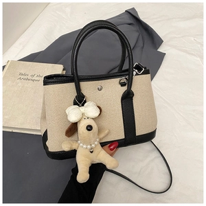 Detail of canvas bucket bag with black leather trim and cute puppy charm accessory