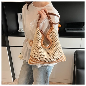 Detail of bohemian hollow woven tote bag featuring brown leather straps and striped base
