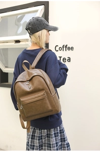 Detailed side view of vintage brown leather backpack with rabbit emblem in cafe setting