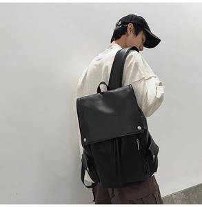 Side view of large black leather backpack showing side pocket and metal clasp detail