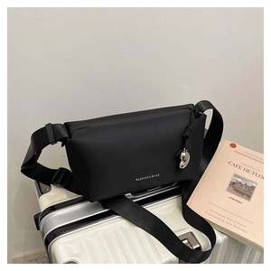 Détail du sac bandoulière en nylon noir avec pendentif cœur sur une valise