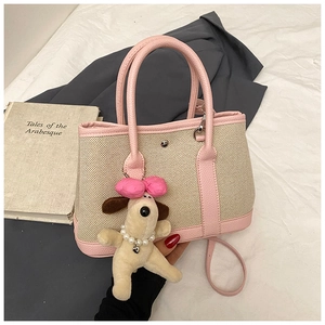 Detail of pink faux leather and beige canvas tote bag with a cute plush puppy charm