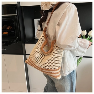 Detailed crochet hobo bag in beige and brown stripes worn by model in home setting