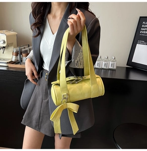 Vue détaillée du sac Boston jaune vif avec un charm nœud élégant et une texture en cuir