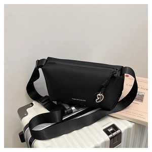 Gros plan d'un sac bandoulière en nylon noir avec breloque cœur et logo blanc chic