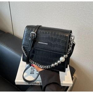 Detail of black crocodile texture bag with silver chain and large pearl accent