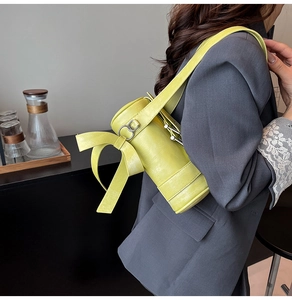 Detail of lime green cylinder bag featuring a large decorative leather bow and silver ring