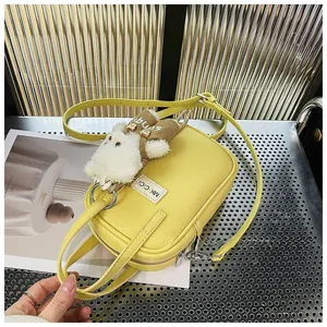 Detail of yellow lychee grain leather crossbody bag with a cute plush rabbit charm